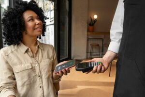 Une cliente paye par carte bancaire dans un café.